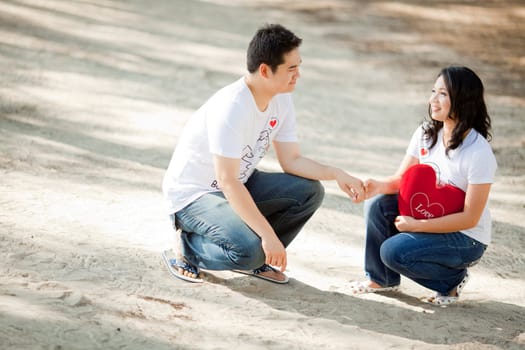 young boy holding his pretty girlfriend hand on the beach