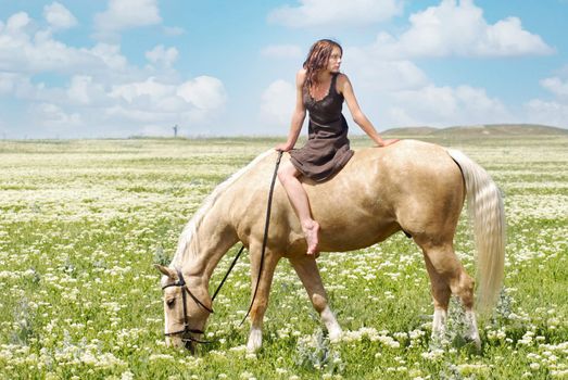 Photo of the small woman on a big horse in summer field