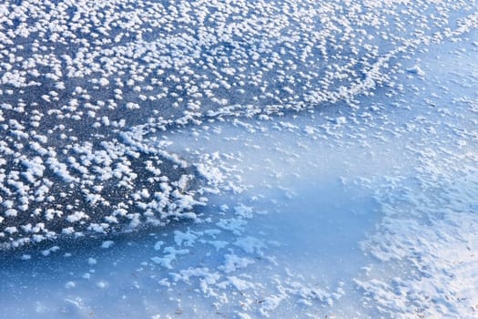 Frozen river surface with the rime as a randomly placed snowflakes