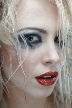 Blond female witch with strange makeup. Studio photo