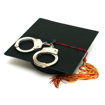 A mortarboard and pair of handcuffs are isolated for police graduates.