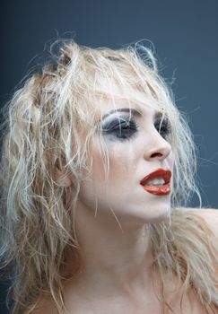 Blond female witch with strange makeup. Studio photo