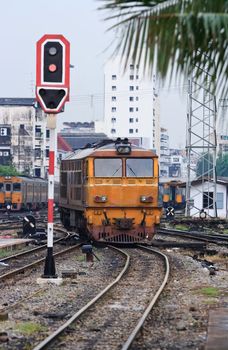 Orange Train locomotive approaching to Bangkok Railway Station Thailand with Red Train Signals