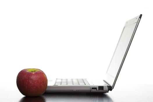 Open laptop sideways on with a fresh red apple in an education concept.