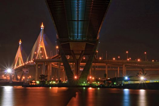 The Industrial Ring Bridge shines at dusk in Thailand with central perspective. The Bridge cross over ChaoPhraya River and Bangkok Harbor