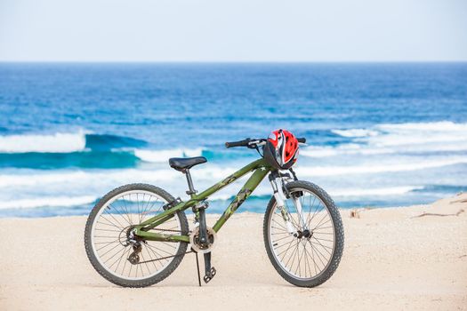 Bicycle with helmet, stand on coast line.