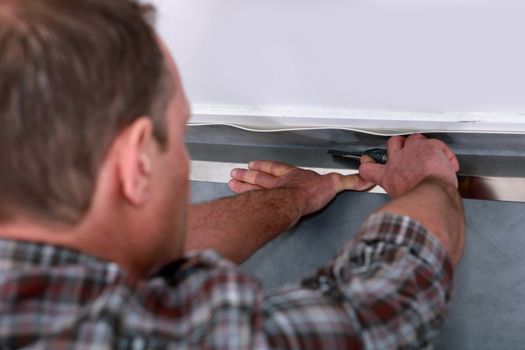 Tradesman laying down linoleum flooring