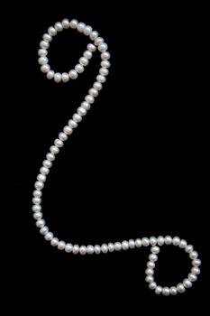 White pearls on the black velvet background 
