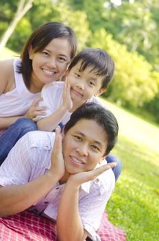 Asian family lying outdoors smiling