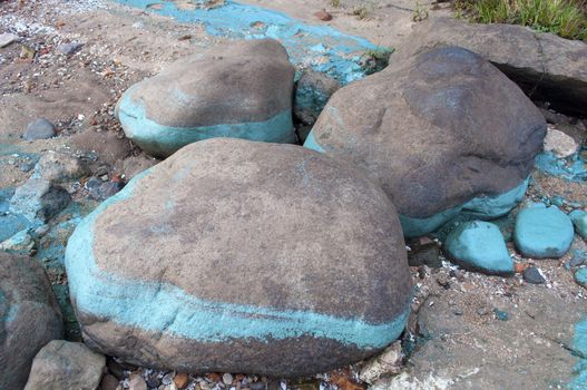 Chemical waste dye on boulders on the river
