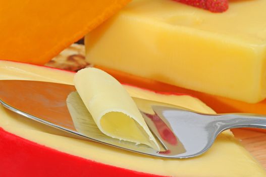 Slicing delicious gouda cheese with additional cheeses in backgound.