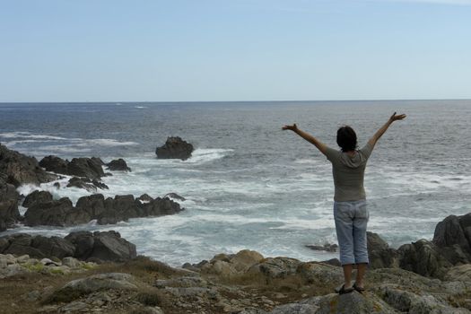 happy woman with arms wide open at the coast