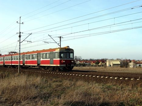 Small train coming back to Wroclaw city in Poland. Passing village and open fields.