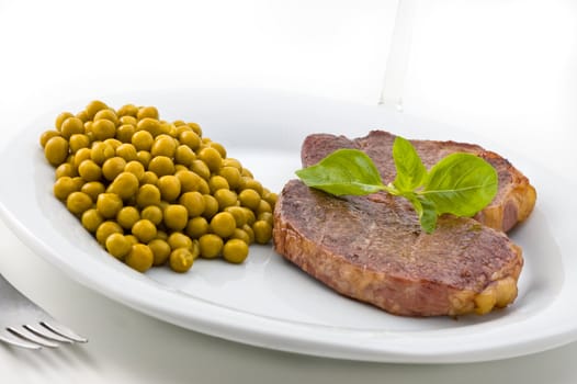 Dish of meat and peas with basil, studio shot.