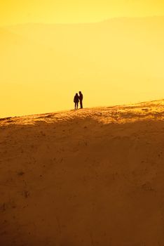 solitude, silhouettes of a man and a woman standing on the hill and holding hands