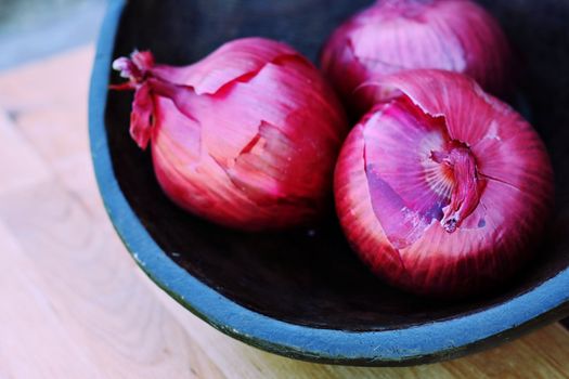 Red onions in a hand carved wooden bowl