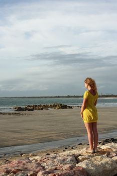 The young girl in a yellow dress on a coast of ocean