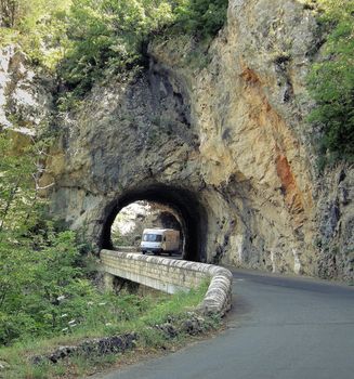 a camper van is passing under a tunnel on a narrow winding road 
