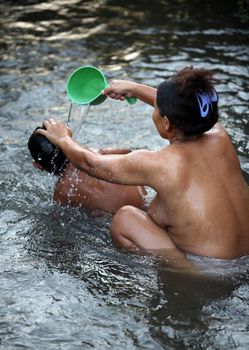 Mother bathes the child in the river. Indonesia. Bali