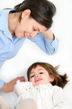 Portrait of mother and her daughter laying on floor. Isolated on white background.