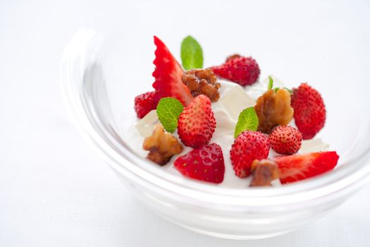 Close up of yogurt dessert with strawberries and caramelized nut dressing