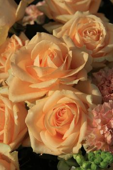 Floral arrangement with soft orange roses and carnations