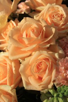 Floral arrangement with soft orange roses and carnations