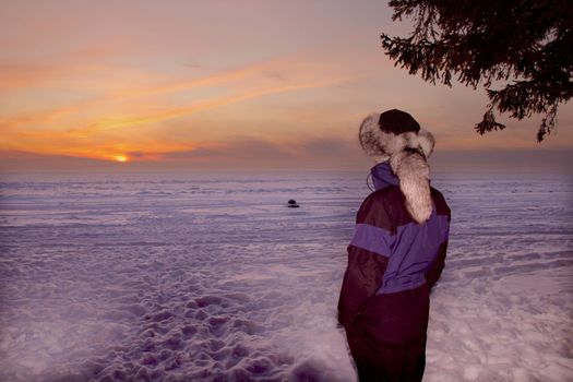 A portrait of man is in a fur cap in winter sunset