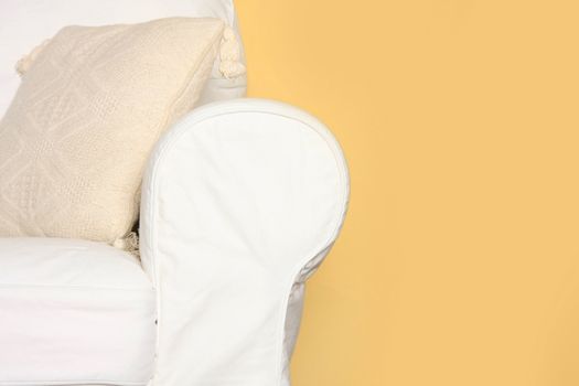 Details shot of a white couch near yellow wall