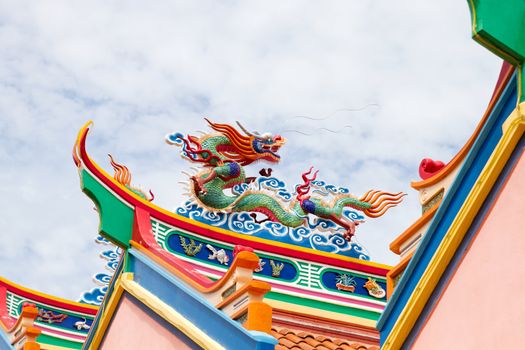Colorful Chinese Dragon Sculpture on Temple Roof Top Against Blue Sky