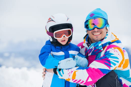 portrait closeup of happy and smiling father and son in ski goggles and a helmet