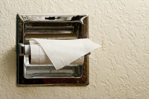 A roll of toilet paper on a dirty holder that is almost empty