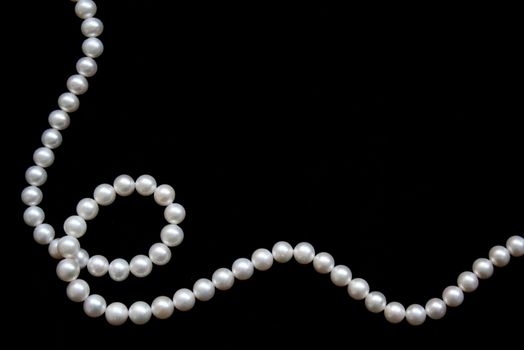 White pearls on the black velvet background 