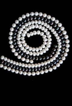 White and black pearls on a black velvet background 
