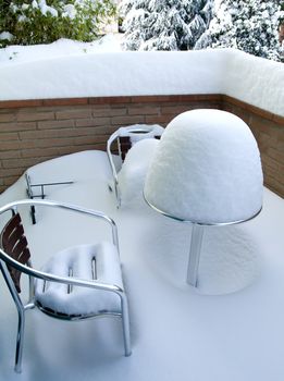 Table and chairs covered in snow a winter day at Castelvetro