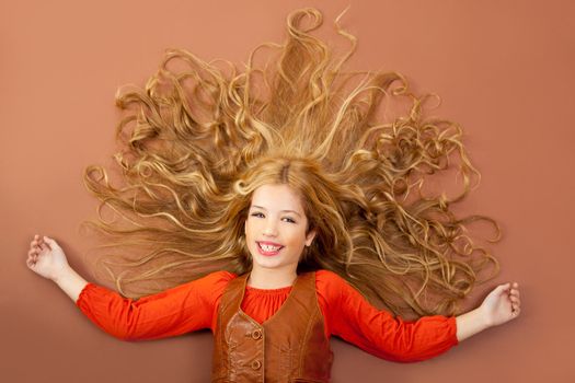 autumn fall little blond girl on brown background and long spreaded hair