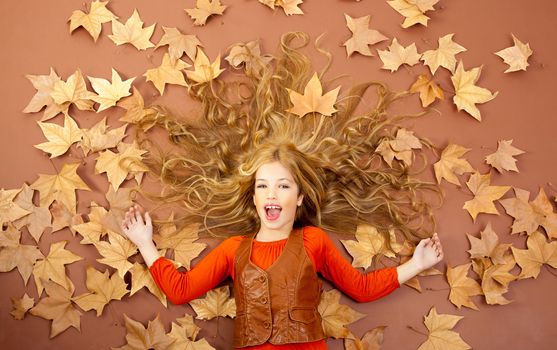 autumn fall little blond girl on dried tree leaves background and long spread hair