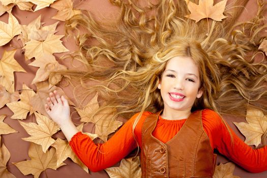 autumn fall little blond girl on dried tree leaves background and long spread hair