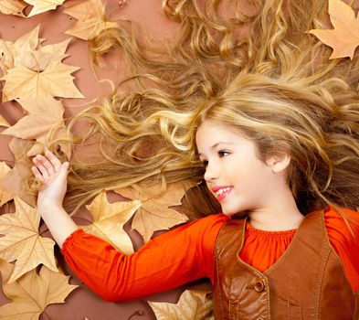 autumn fall little blond girl on dried tree leaves background and long spread hair