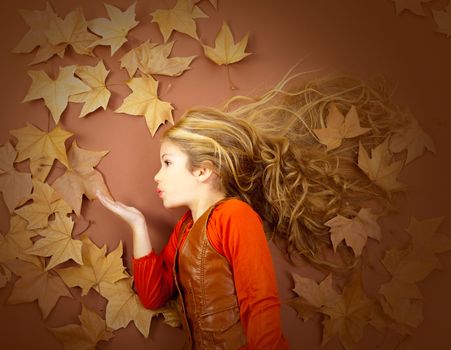 autumn fall little blond girl on dried tree leaves blowing wind with lips