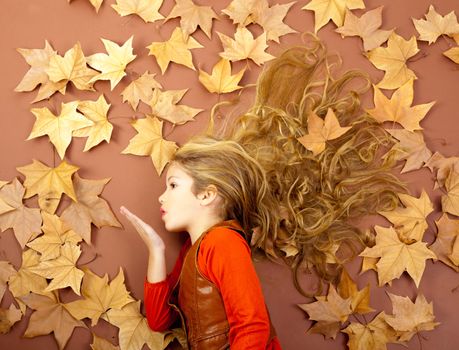 autumn fall little blond girl on dried tree leaves blowing wind with lips