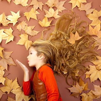 autumn fall little blond girl on dried tree leaves blowing wind with lips