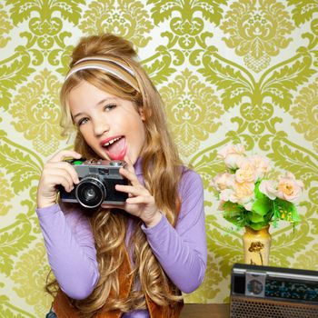 hip retro little girl shooting photo with vintage camera on wallpaper