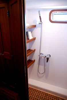 Impression of the interior of a small deluxe yacht, showing the intimate forward cabin and the heads compartment, displaying the v-shaped bunk beds, 360 degrees mahogany wood panelling, the shower and toilet compartment, including sink, and the custom built storage cabinets