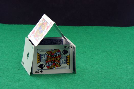 house made of playing cards on green felt with copy space black