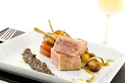 gourmet tuna dish with garnished vegetables and wine.