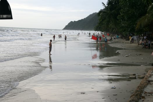 people walking and swimming on the beach