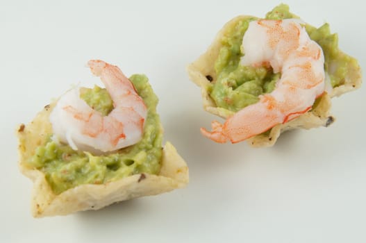 Nacho with guacamole and a shrimp on top.
