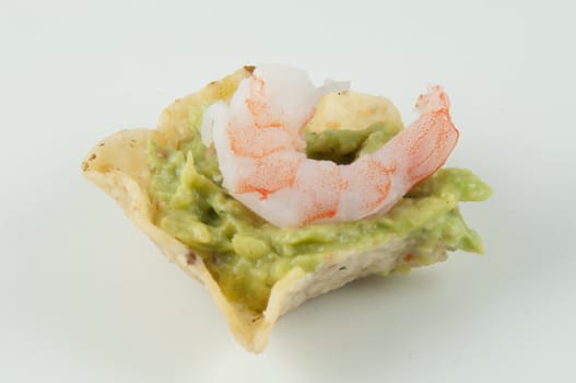 Nacho with guacamole and a shrimp on top.