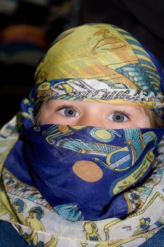 Curious European child dressed in headscarf in the Arabian manner